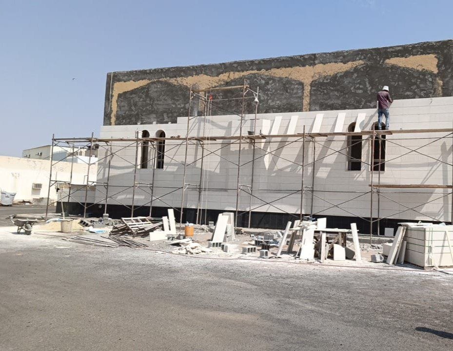 المسجد أثناء التنفيذ: واجهة محاطة بسقالات والعامل على ارتفاع الواجهة