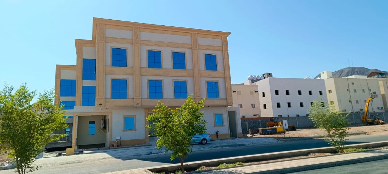 العمارة السكنية بعد التشطيب بواجهتها البيج ونوافذها الزرقاء